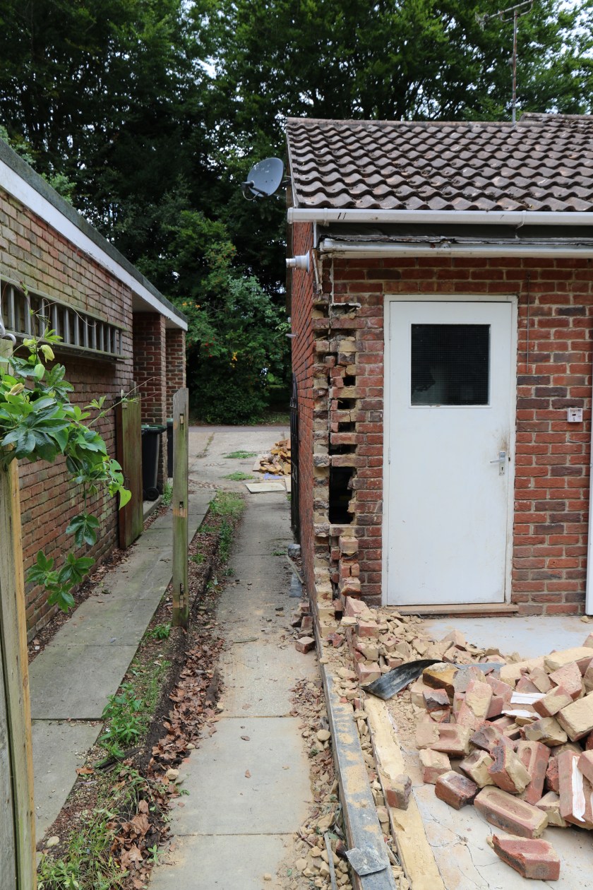 Conservatory - Neighbours fence removed. Large holes in garage wall.